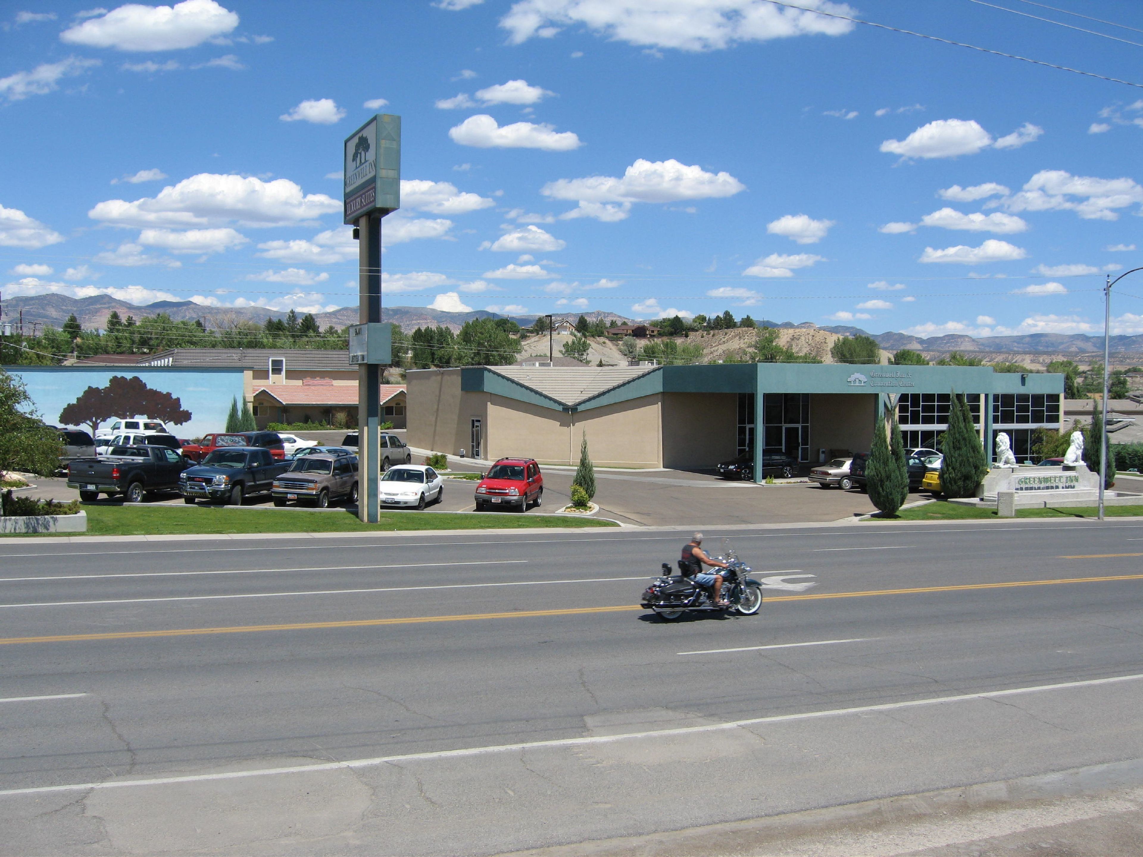 A building with a green roof and a parking lot with several cars.