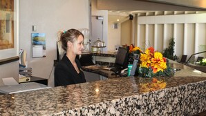A reception desk with a granite countertop, a computer, and a vase of flowers. - The Greenwell Inn (Price)