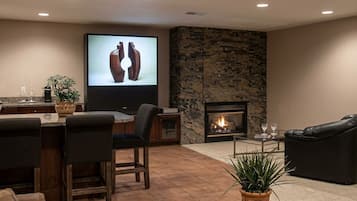A modern living room with a fireplace, a television, and a dining area with bar stools.