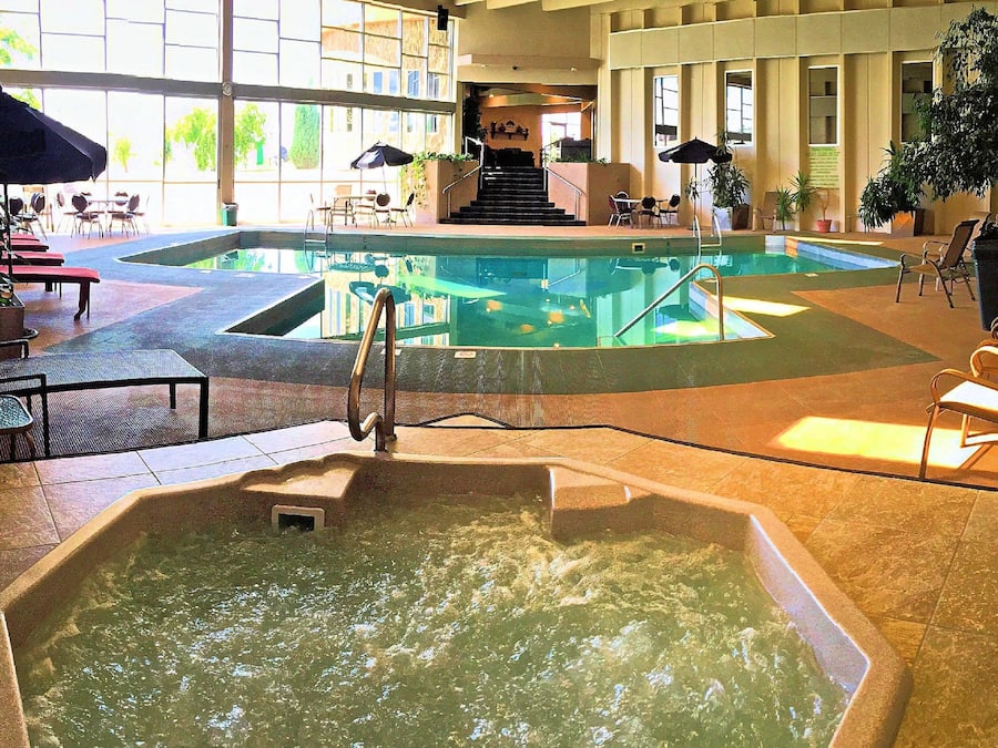 Una piscina techada, sombrillas, sillones reclinables de piscina