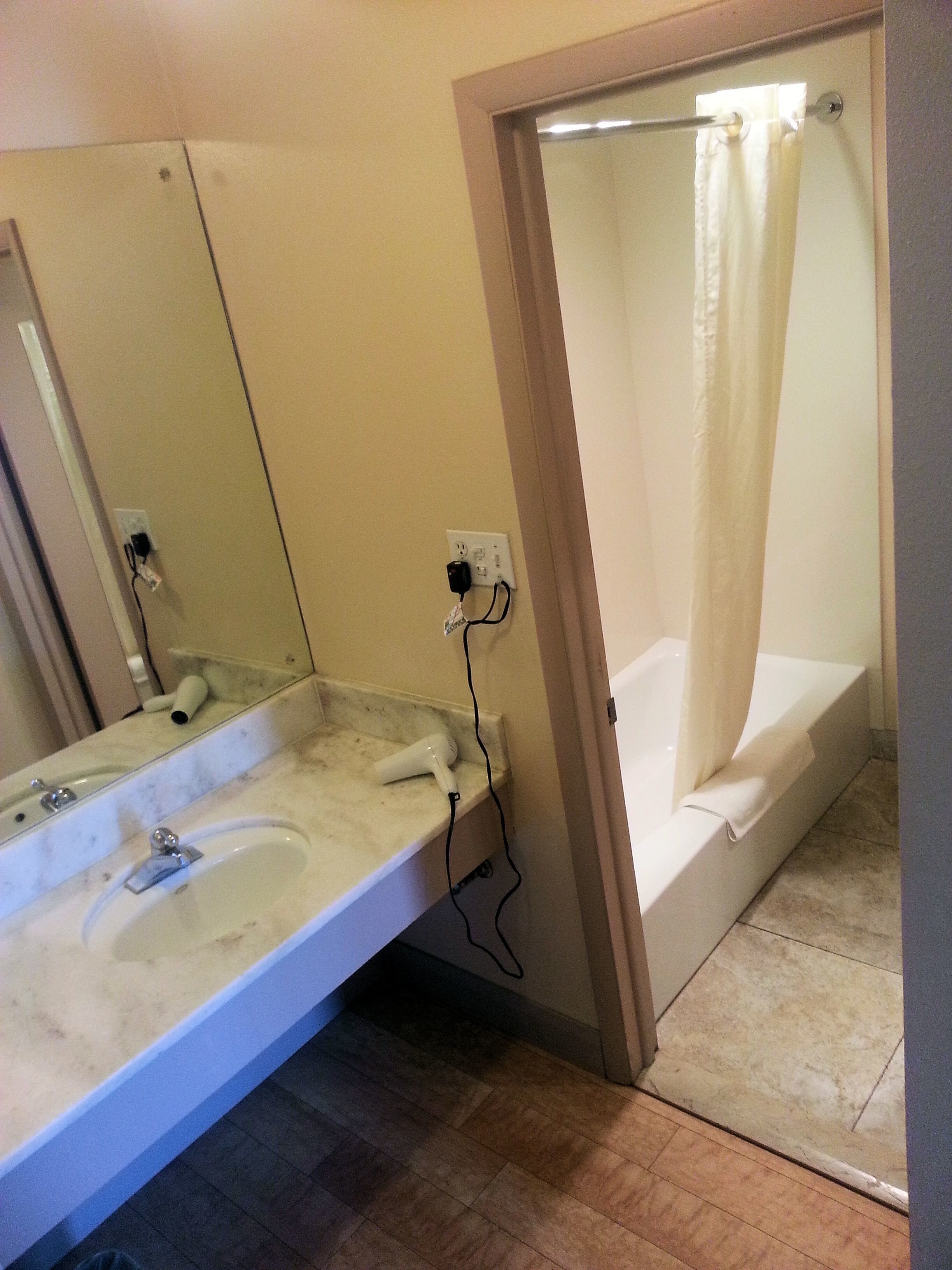 A bathroom with a sink, mirror, and shower.