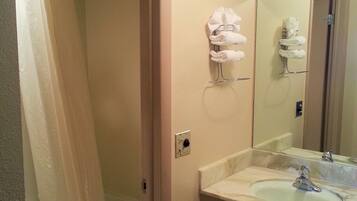 A bathroom with a shower, a sink, and a towel rack.