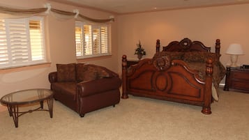 A bedroom with a wooden bed, a leather sofa, a glass coffee table, and a nightstand with a lamp.