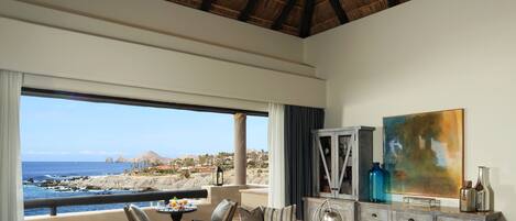 A spacious living room with a large sofa, a coffee table, and a view of the ocean.