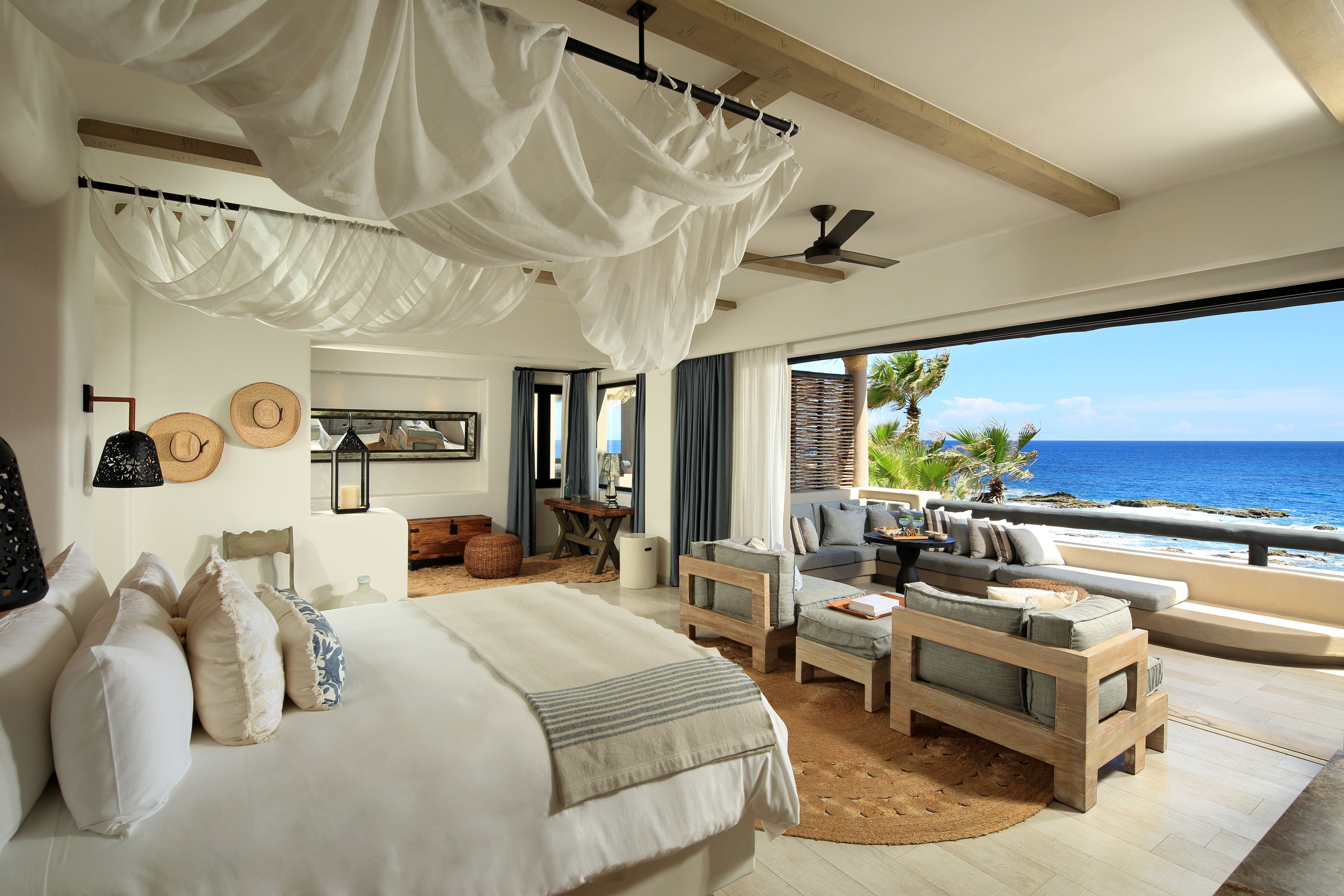 A spacious bedroom with a large bed, a wooden sofa, and a view of the ocean.