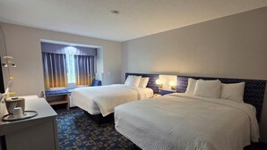 A hotel room with two beds, a desk, and a window with curtains.