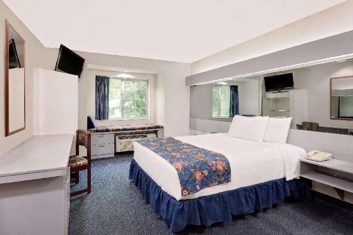 Habitación de hotel con cama, escritorio, silla y televisor.