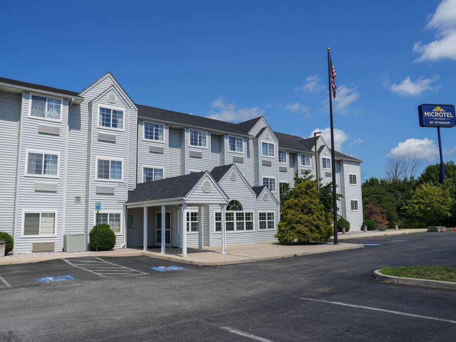 A Microtel Inn & Suites building with a covered entrance, parking lot, and a flagpole with an American flag.