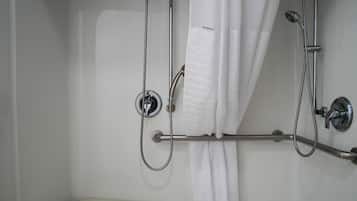 A shower area with a curtain, a handheld showerhead, and a wall-mounted faucet.