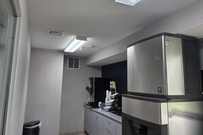 A compact kitchenette with a stainless steel refrigerator, a coffee maker, and a trash bin. - Microtel Inn & Suites by Wyndham Hagerstown by I-81 (Hagerstown)
