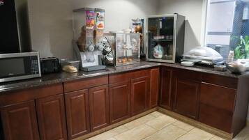 Una cocina equipada con microondas, tostadora, cafetera y refrigerador.