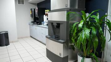 A kitchen with a built-in espresso machine, a trash bin, and a potted plant.