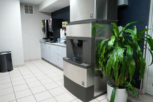 A kitchen with a built-in espresso machine, a trash bin, and a potted plant.