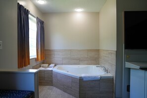 A modern bathroom with a freestanding bathtub, a vanity with a mirror, and a window with curtains. - Microtel Inn & Suites by Wyndham Hagerstown by I-81 (Hagerstown)