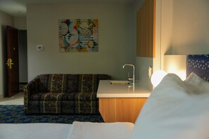 A hotel room with a bed, a small kitchenette, a sofa, and a wall-mounted artwork. - Microtel Inn & Suites by Wyndham Hagerstown by I-81 (Hagerstown)