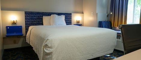 Una habitación de hotel con una cama grande, dos lámparas de noche, un escritorio y una silla.