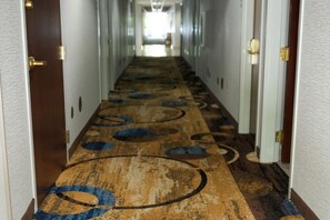 A hotel hallway with a patterned carpet and doors on both sides. - Microtel Inn & Suites by Wyndham Hagerstown by I-81 (Hagerstown)