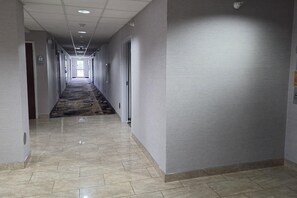 A hotel corridor with a patterned carpet, tiled floor, and doors leading to rooms. - Microtel Inn & Suites by Wyndham Hagerstown by I-81 (Hagerstown)