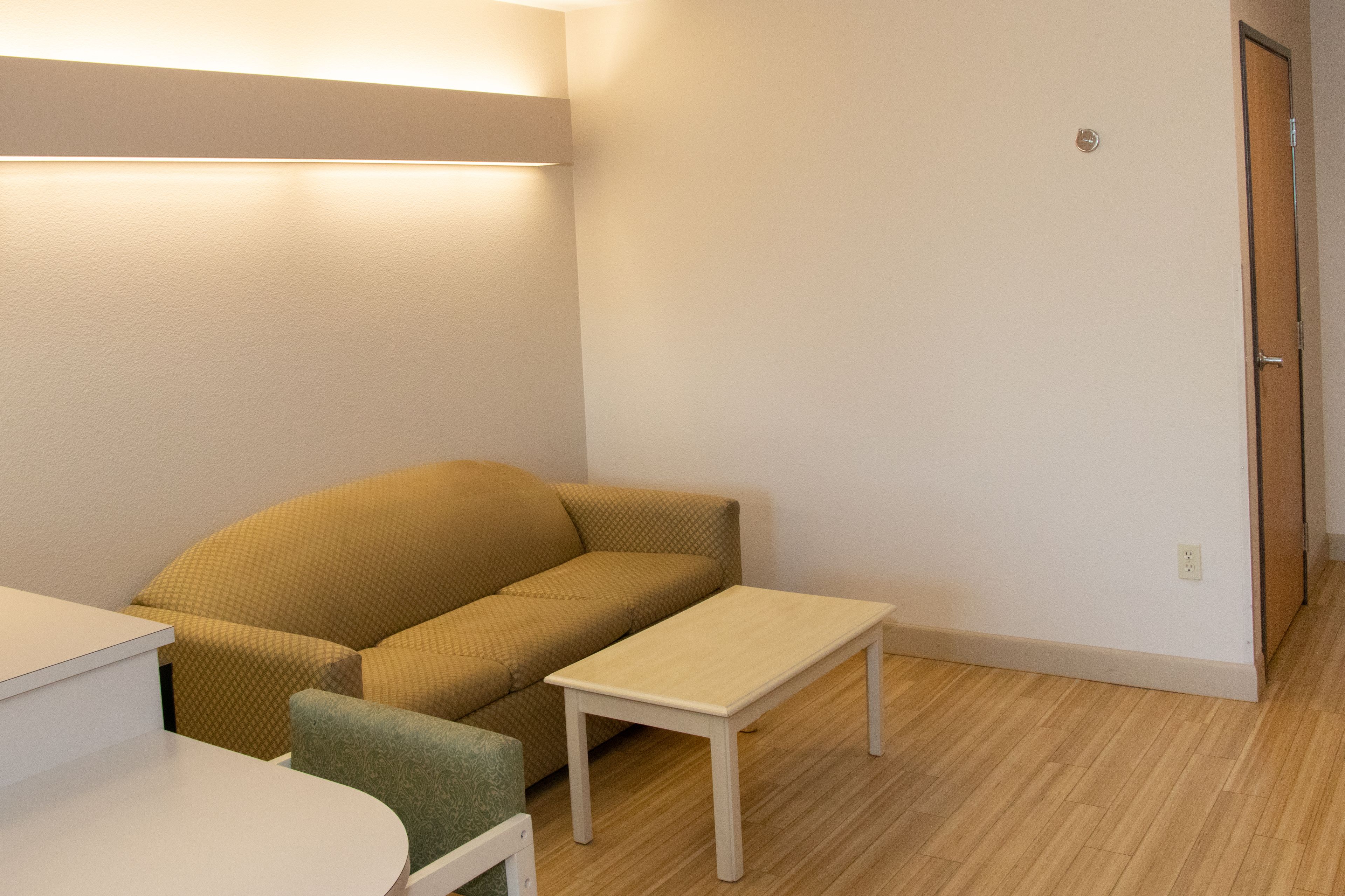 A small, neatly arranged room with a sofa, a small table, and a door.