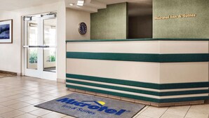 A reception desk with a clock, a green and white color scheme, and a sign for 'Microtel Inn & Suites'. - Microtel Inn & Suites by Wyndham Lodi/North Stockton (Lodi)