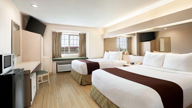 A hotel room with two beds, a desk, a TV, and a window with curtains. - Microtel Inn & Suites by Wyndham Lodi/North Stockton (Lodi)