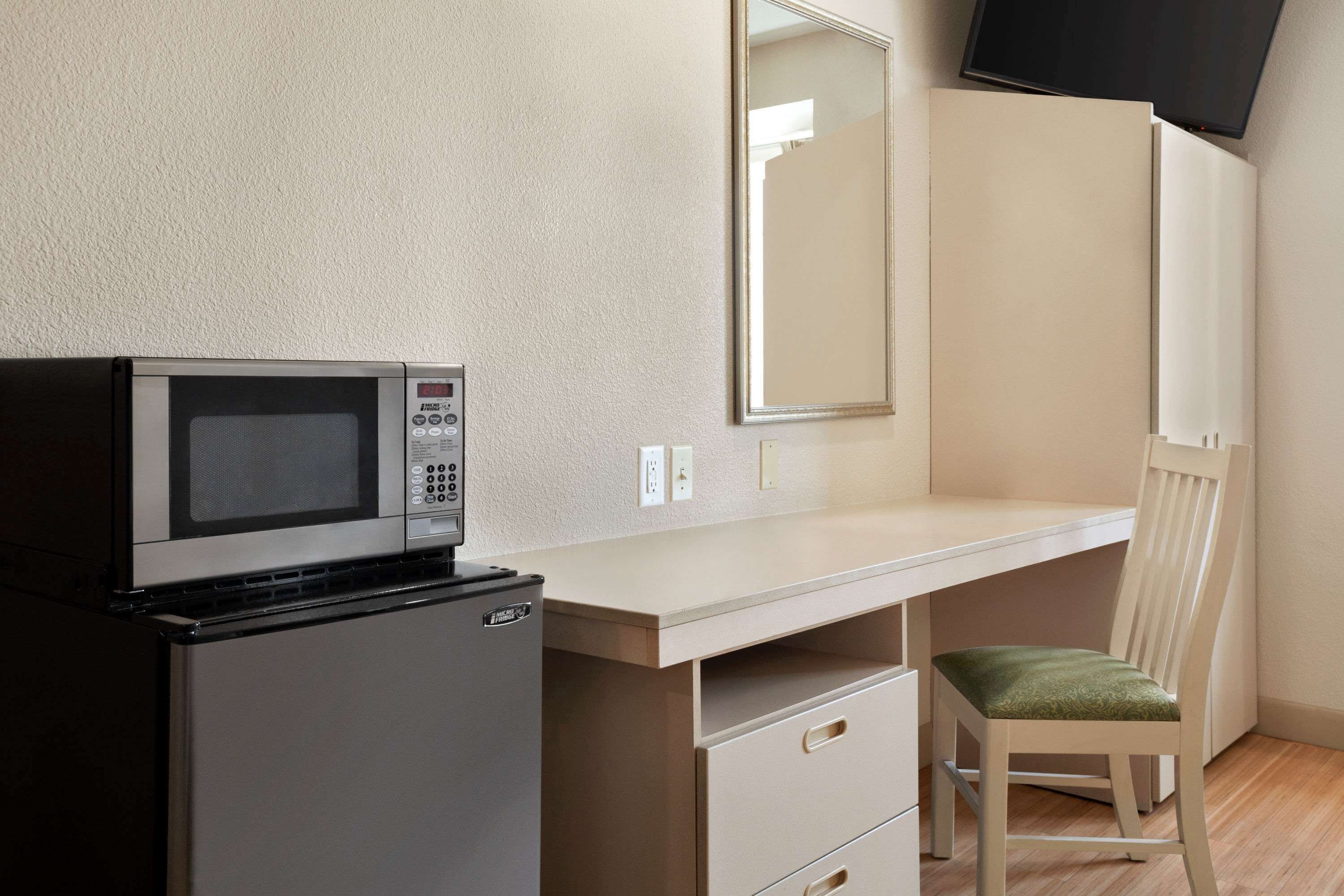 Une petite cuisine équipée d’un micro-ondes, d’un petit réfrigérateur, d’un bureau et d’une chaise.