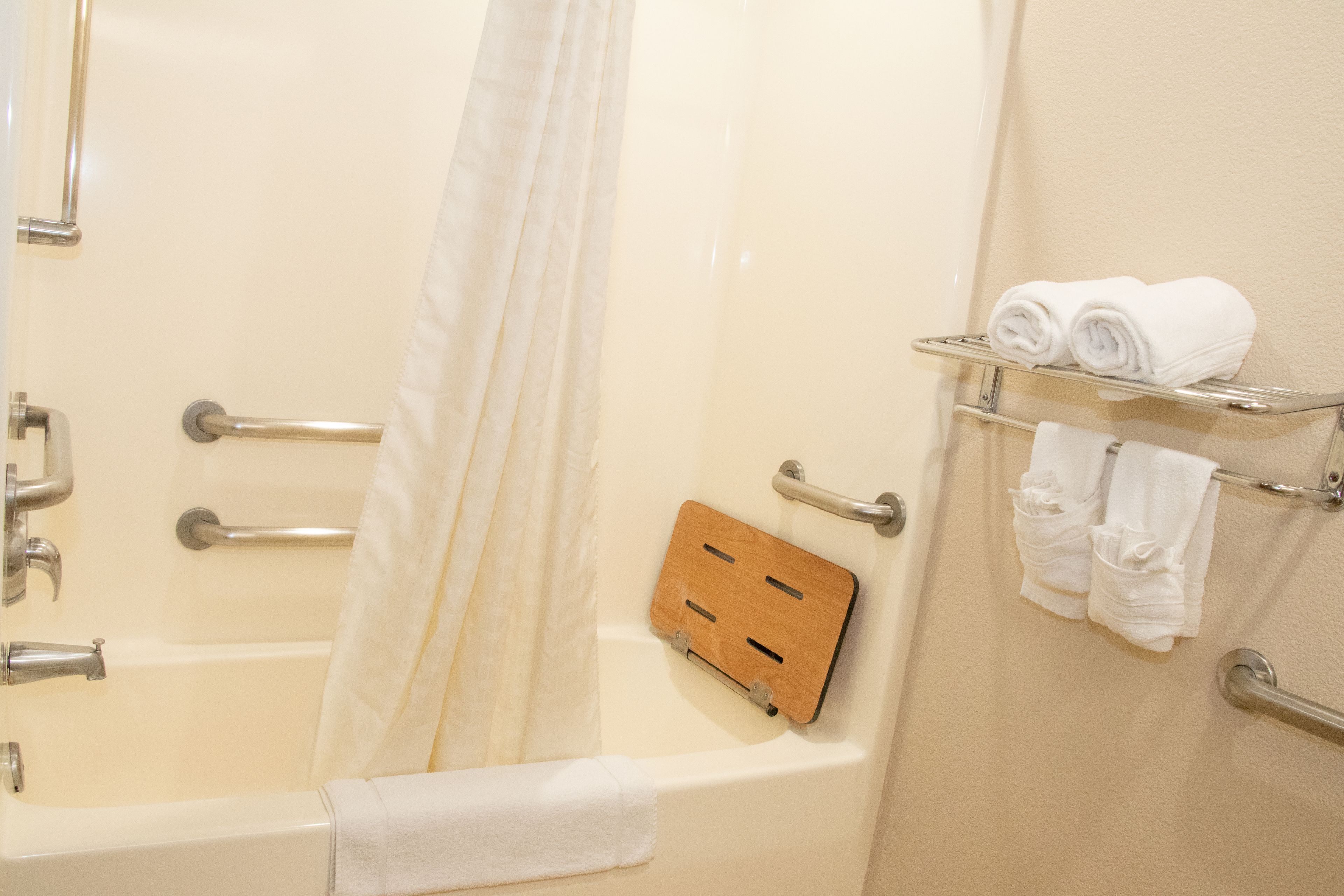 A bathroom with a bathtub, a shower curtain, a towel rack with towels, and a wooden panel.