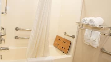 A bathroom with a bathtub, a shower curtain, a towel rack with towels, and a wooden panel.