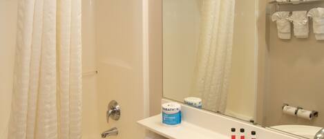A bathroom with a bathtub, toilet, and sink. There are towels and toiletries on the sink.