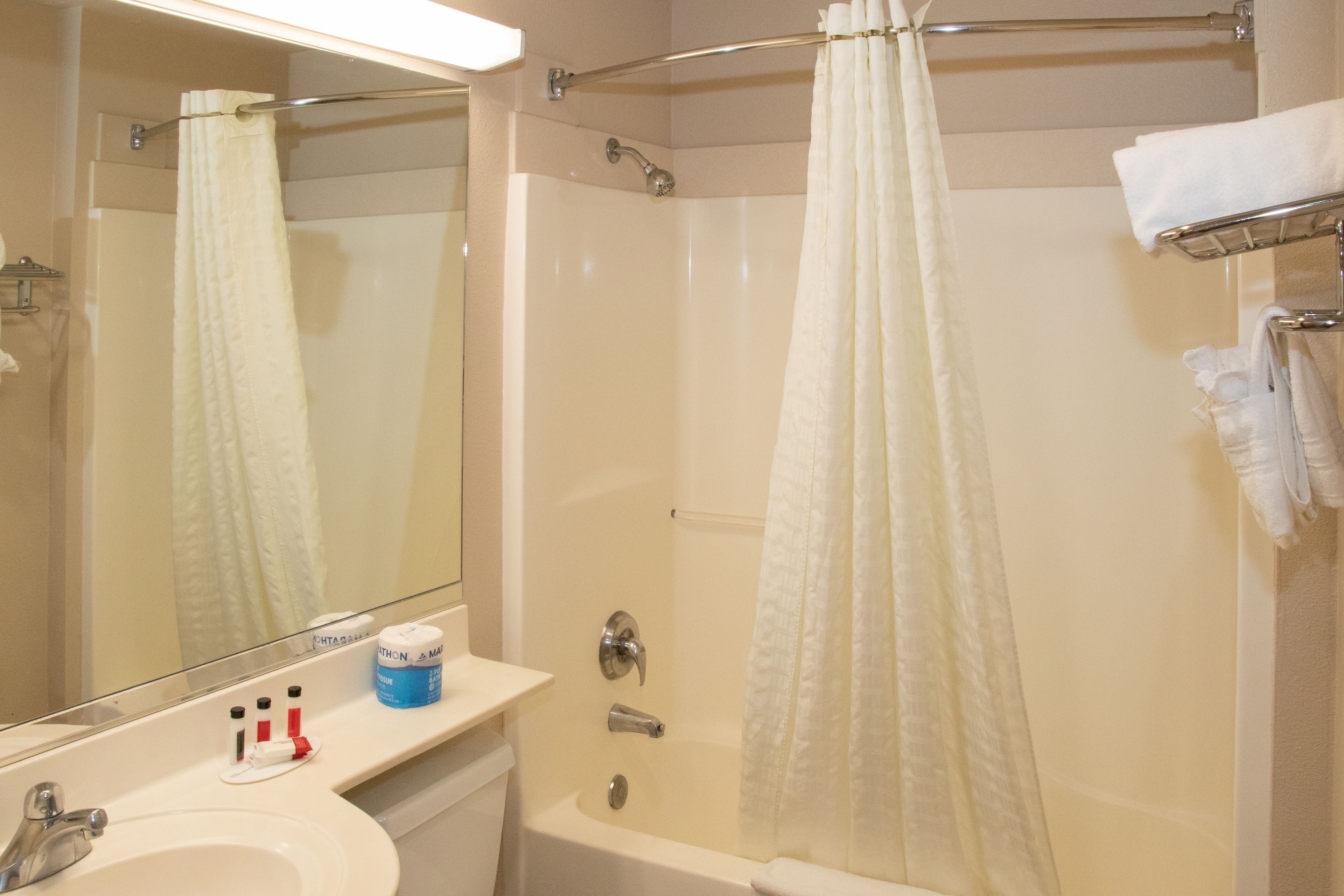 A bathroom with a bathtub, a shower, a sink, and a mirror.