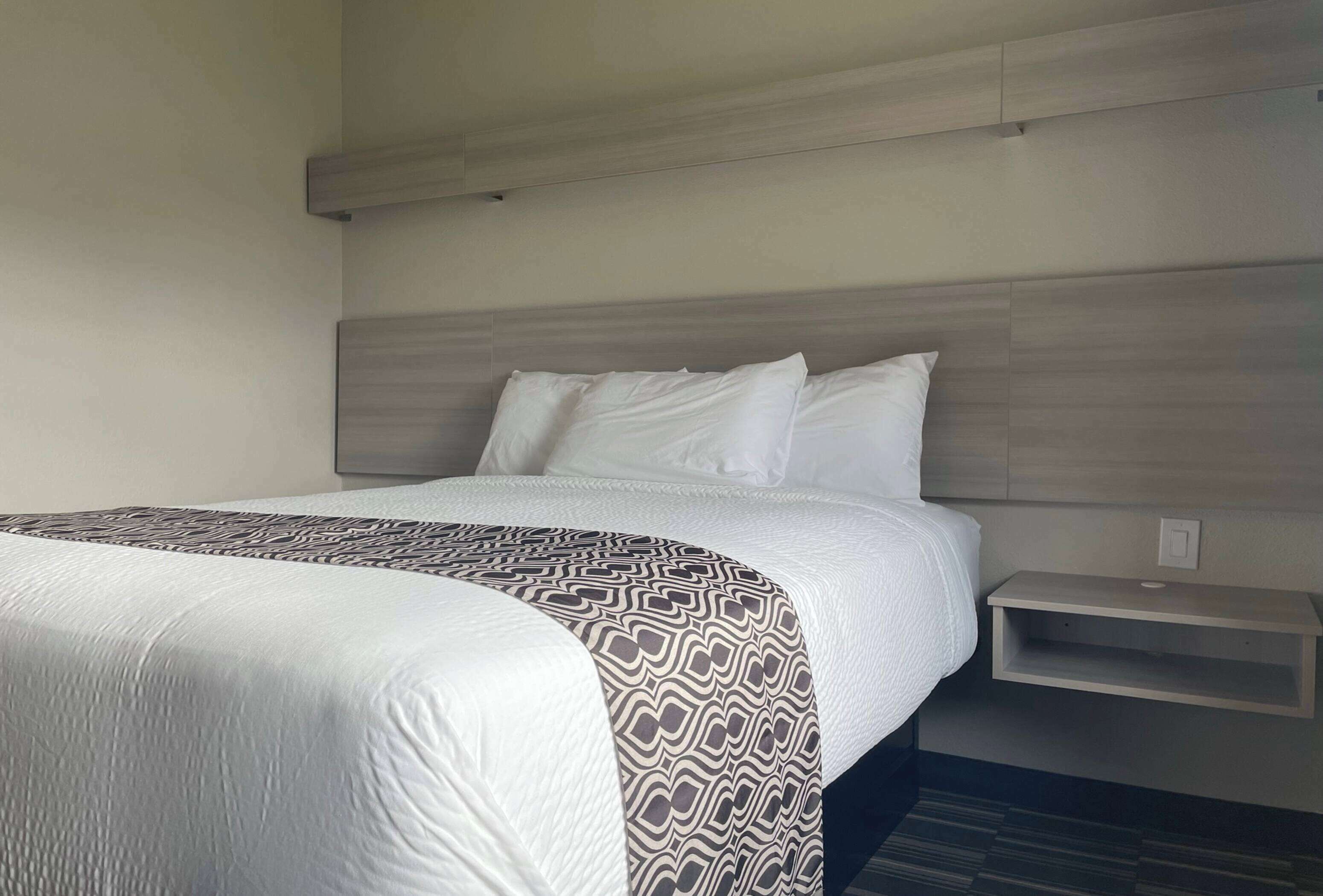 Une chambre d’hôtel avec un grand lit, une table de chevet et une tête de lit.