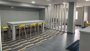 A conference room with a long table and yellow chairs, a patterned floor, and a partition with vertical slats. - Microtel Inn & Suites by Wyndham Bossier City (Bossier City)