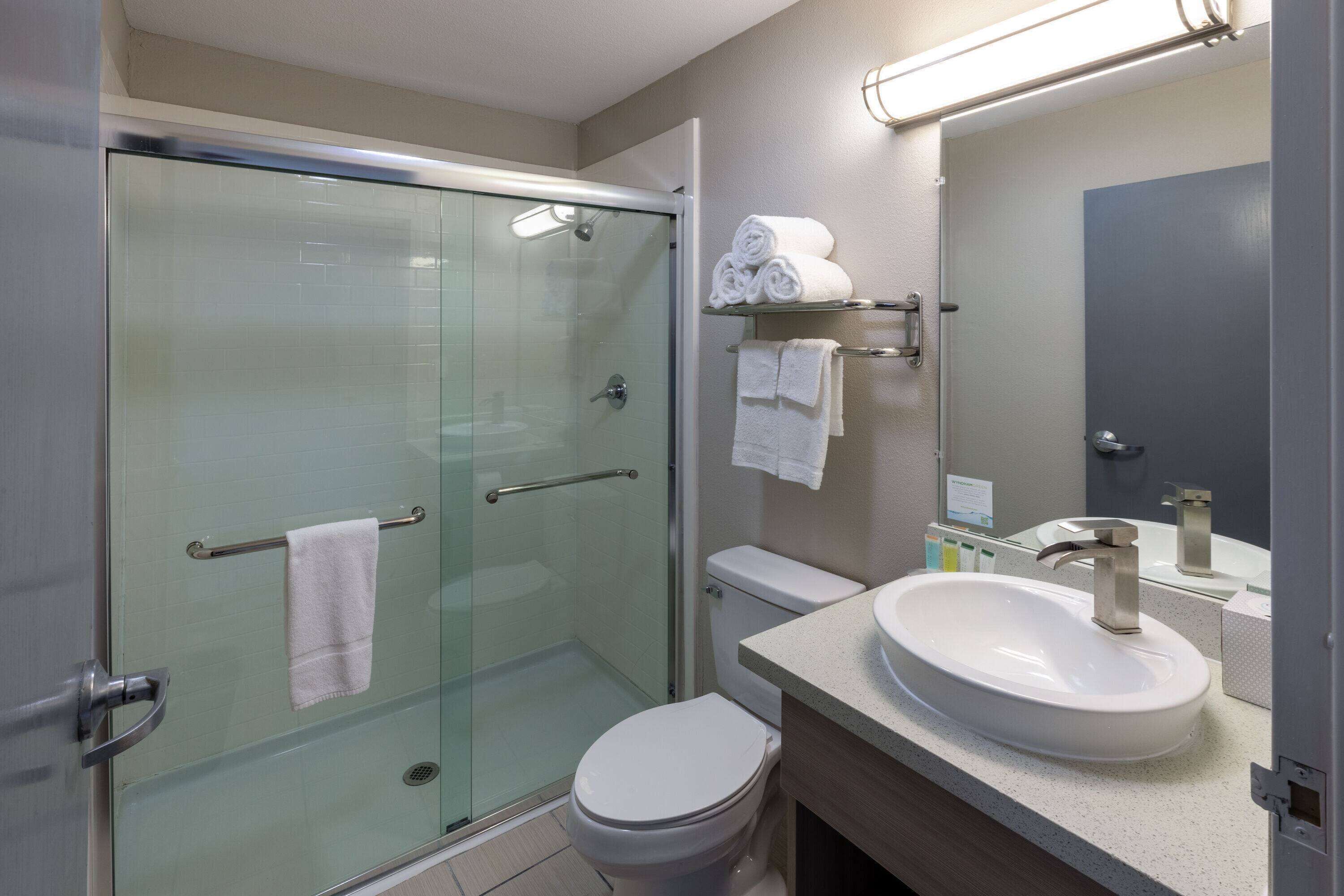 A modern bathroom with a glass-enclosed shower, a white toilet, and a sink with a mirror above it.