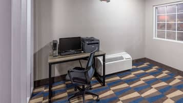 Un petit bureau comprenant un bureau, une chaise, une imprimante et un appareil de climatisation.
