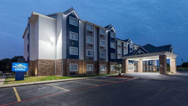 A multi-story hotel with a modern design, featuring a prominent entrance and a parking lot. - Microtel Inn & Suites by Wyndham Bossier City (Bossier City)