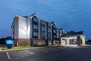 A multi-story hotel with a modern design, featuring a prominent entrance and a parking lot. - Microtel Inn & Suites by Wyndham Bossier City (Bossier City)