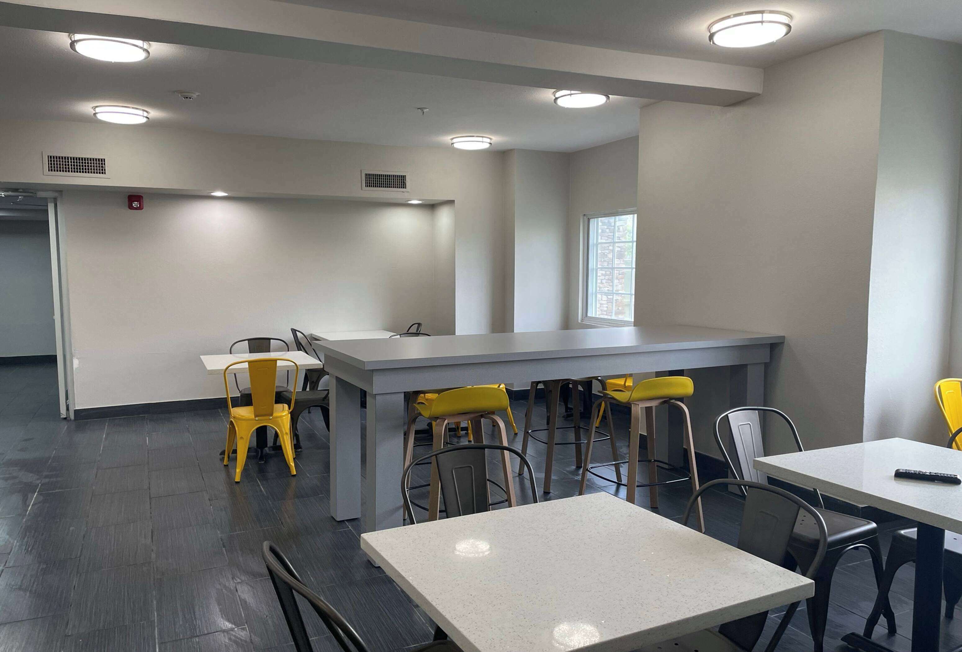 A modern dining area with a long counter, multiple chairs, and tables.