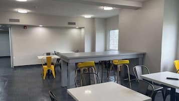 A modern dining area with a long counter, multiple chairs, and tables.