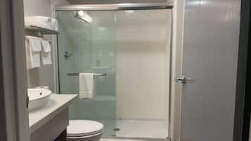 A modern bathroom with a glass-enclosed shower, a toilet, and a sink with a towel rack.