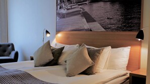 A neatly made bed with pillows, a headboard, and a nightstand with a lamp.