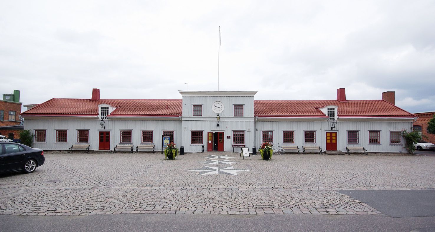 A white building with a red roof, a clock, and a central entrance.