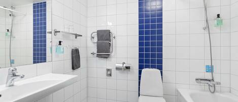 Un baño moderno con lavamanos, inodoro y bañera blancos, paredes con azulejos azules y un box de ducha de vidrio.