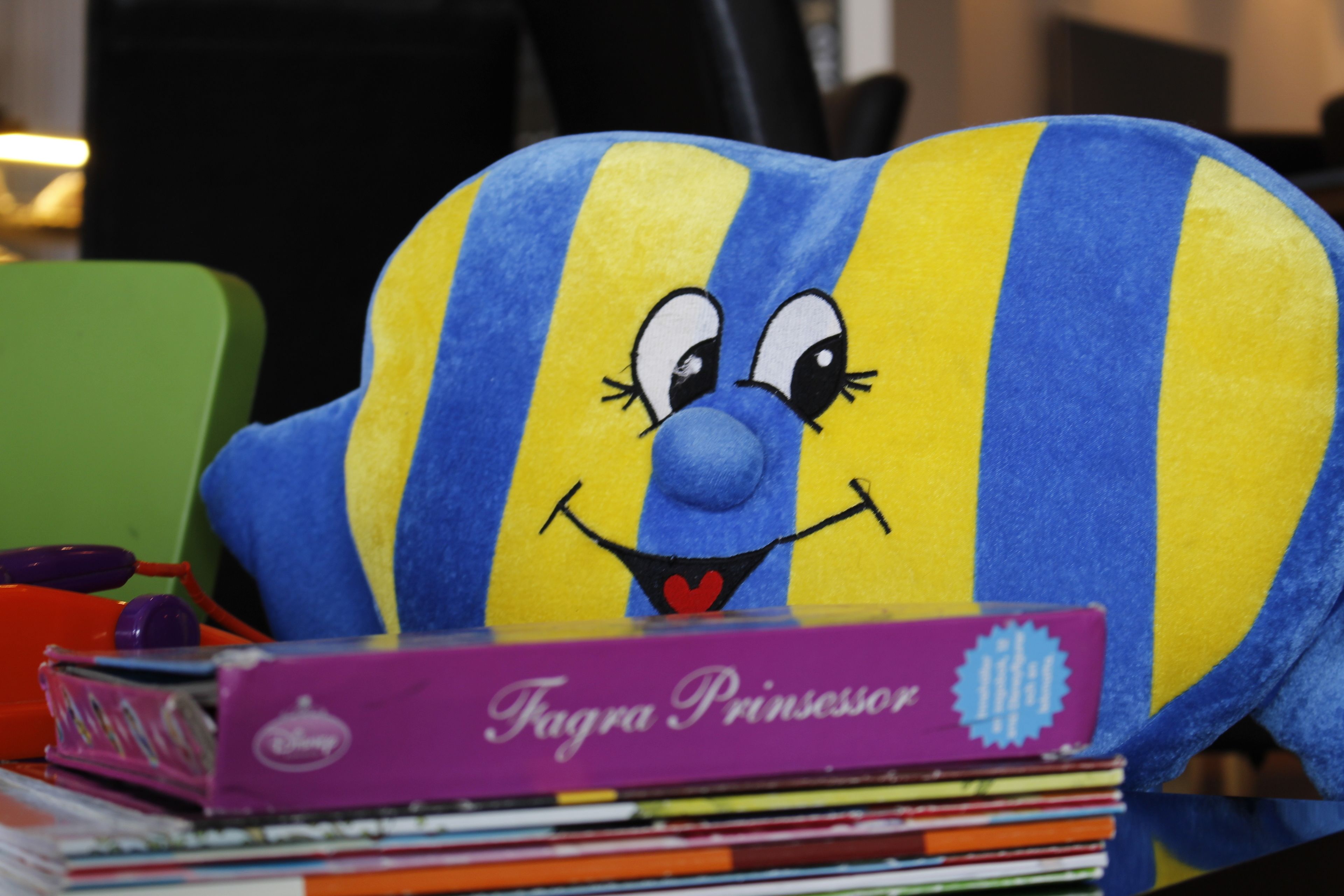 Un peluche con estampado a rayas y rostro, sobre una pila de libros.