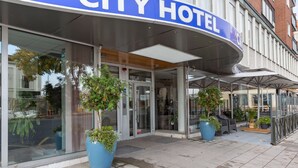 A CITY HOTEL with a modern entrance, glass doors, and potted plants.