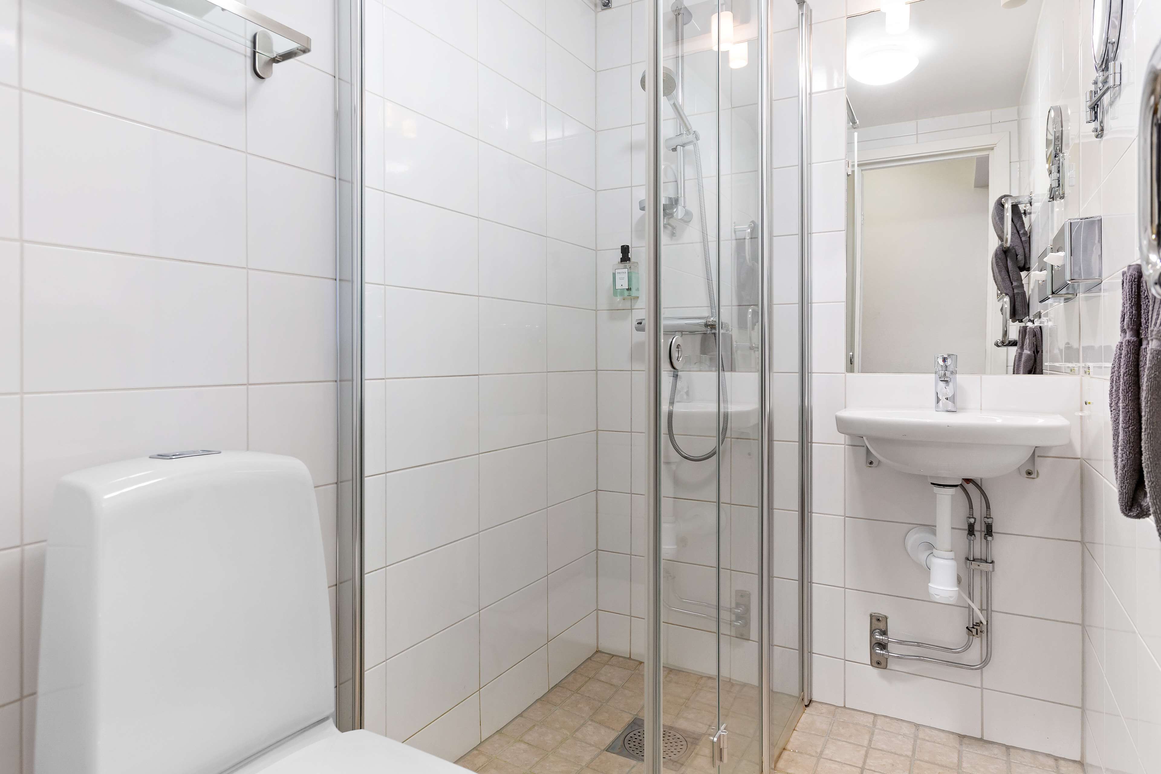 Un baño moderno con ducha envuelta en vidrio, lavamanos blanco y un inodoro.
