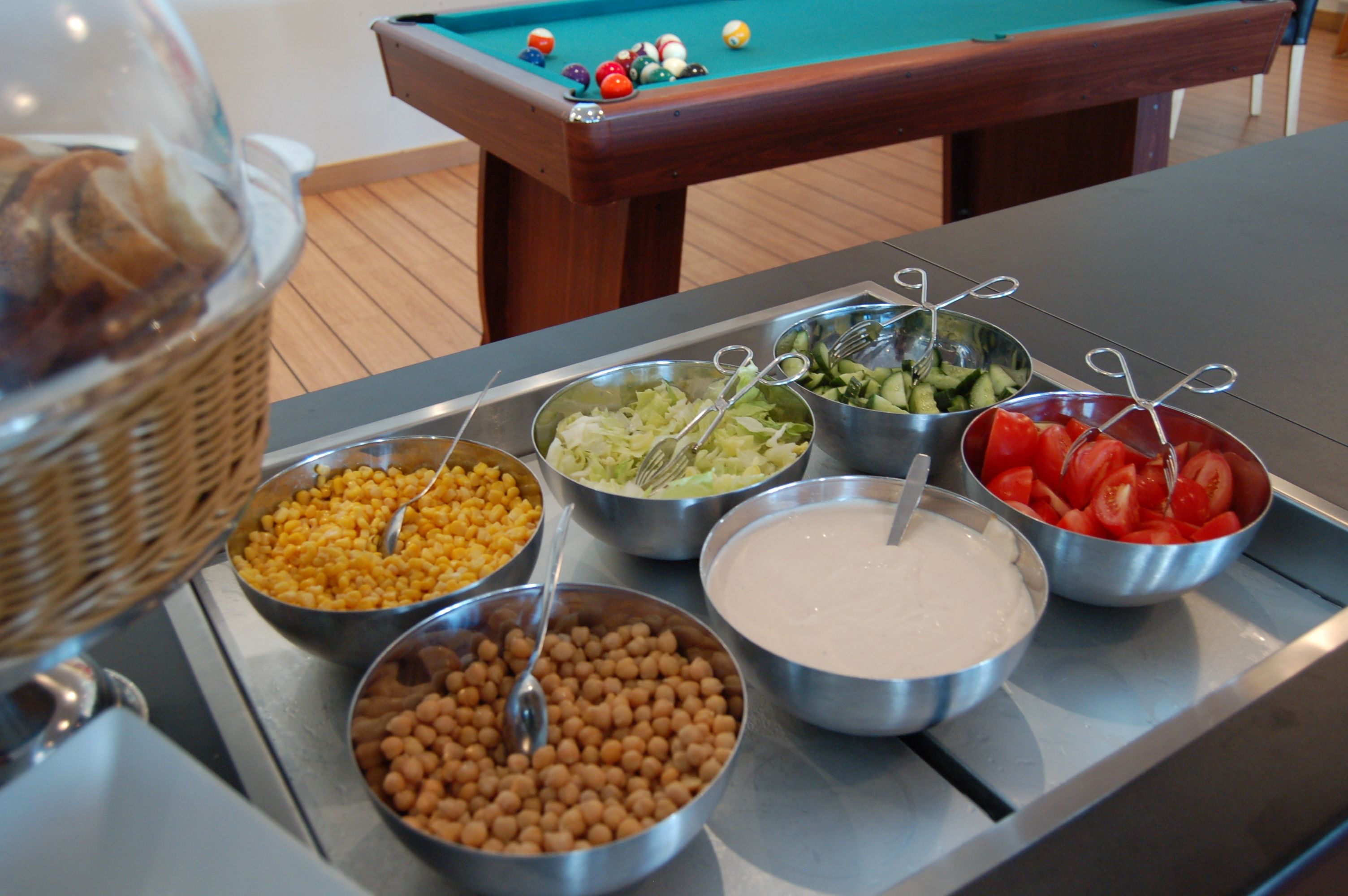 A buffet table with various food items including beans, salad, and sliced tomatoes.