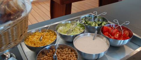 A buffet table with various food items including beans, salad, and sliced tomatoes.