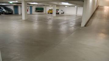 Un estacionamiento vacío con pisos de concreto y pilares blancos.