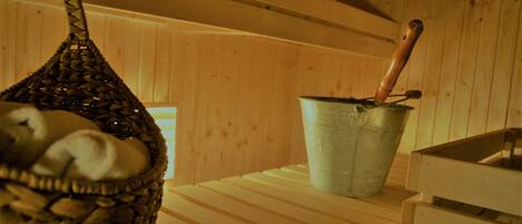 Una sauna de madera con una cesta tejida y un cubo de metal con asa de madera.