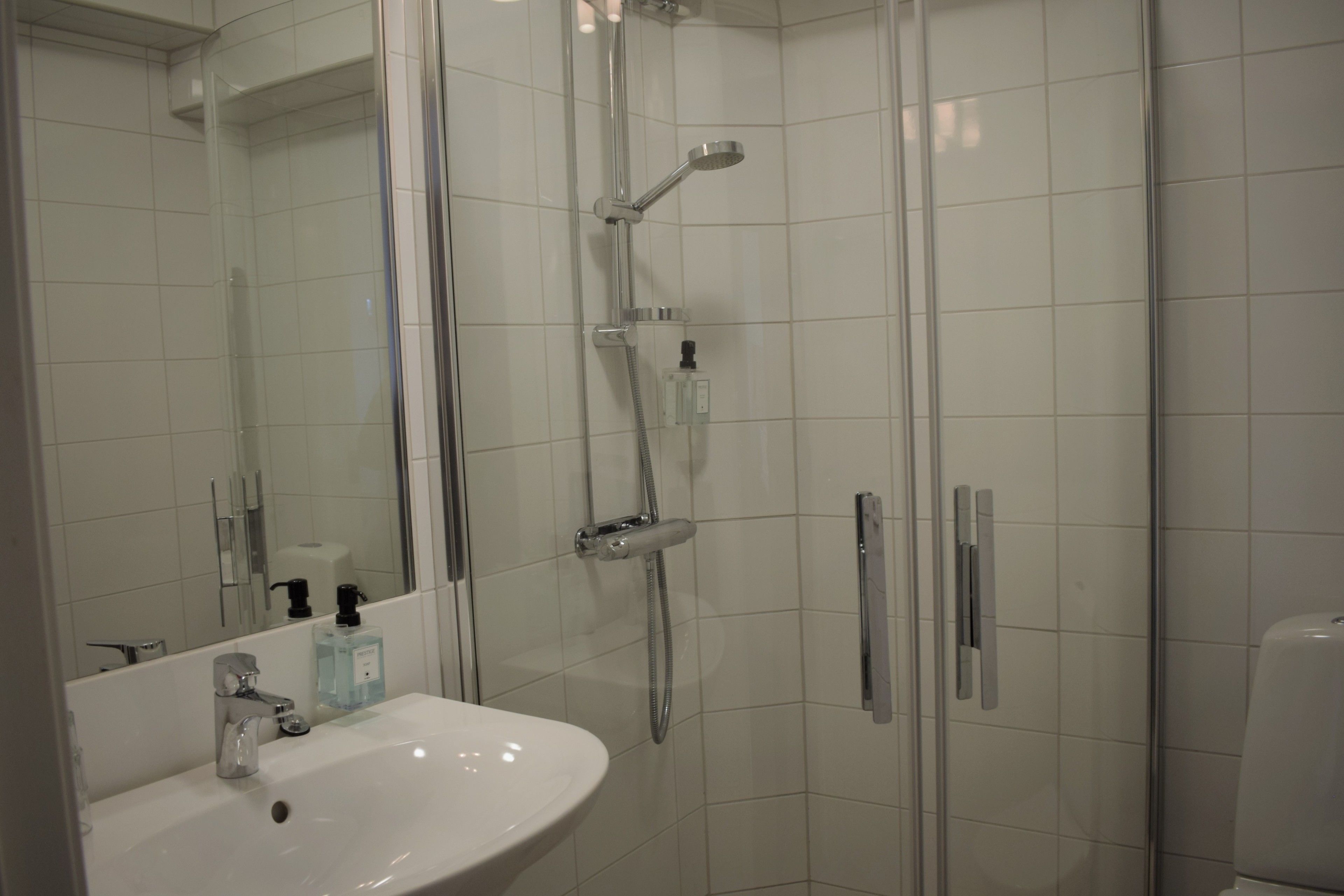 A modern bathroom with a glass-enclosed shower, a white sink, and a mirror.